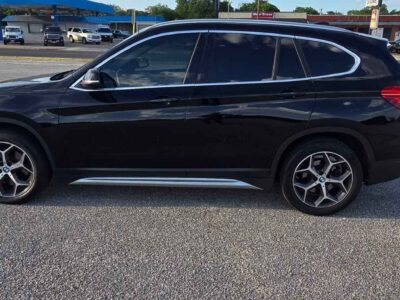 2018 BMW X1 sDrive28i side exterior profile layout highlighting deep Jet Black paint finish and factory alloy wheels