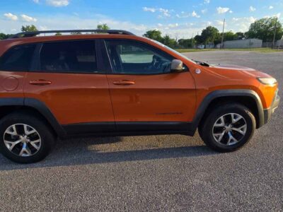 2015 Jeep Cherokee Trailhawk 4WD side exterior view highlighting matte black hood decal, raised off-road ride height, and custom dark alloy wheels